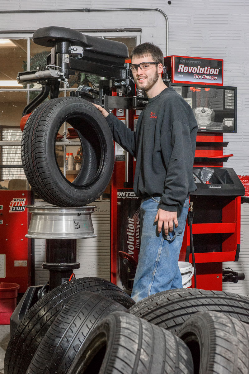 tc-tcr-realshop-berts4.jpg technician smiling with tire and revolution tire changer